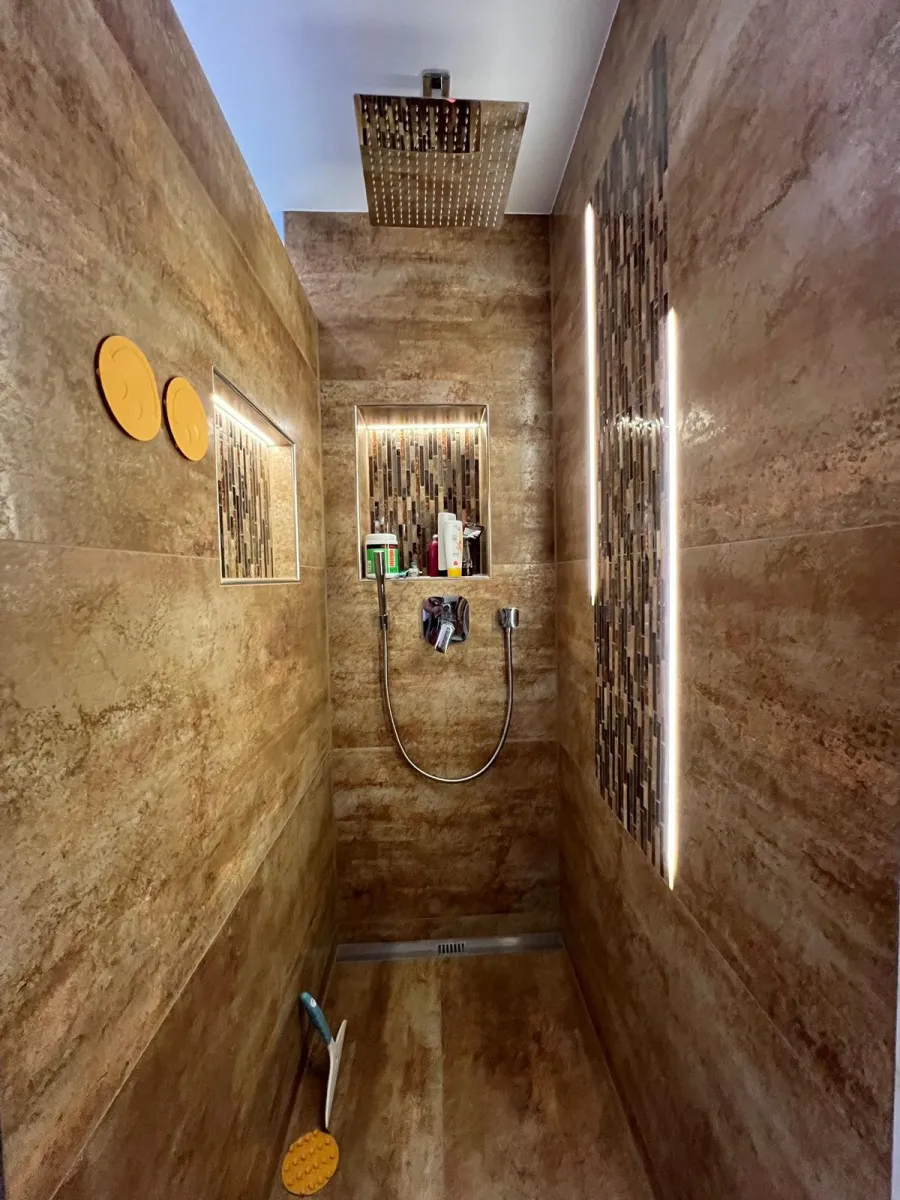 Begehbare Dusche mit Natursteinoptik-Fliesen und goldfarbener Kopfbrause