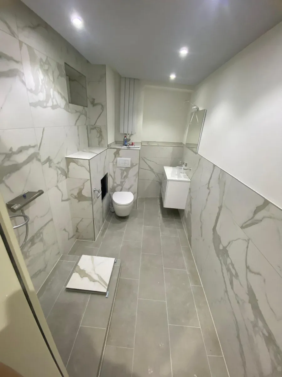 Bad mit großformatigen Marmor-Fliesen, Dusche, Wand-WC und schwebendem Waschtisch