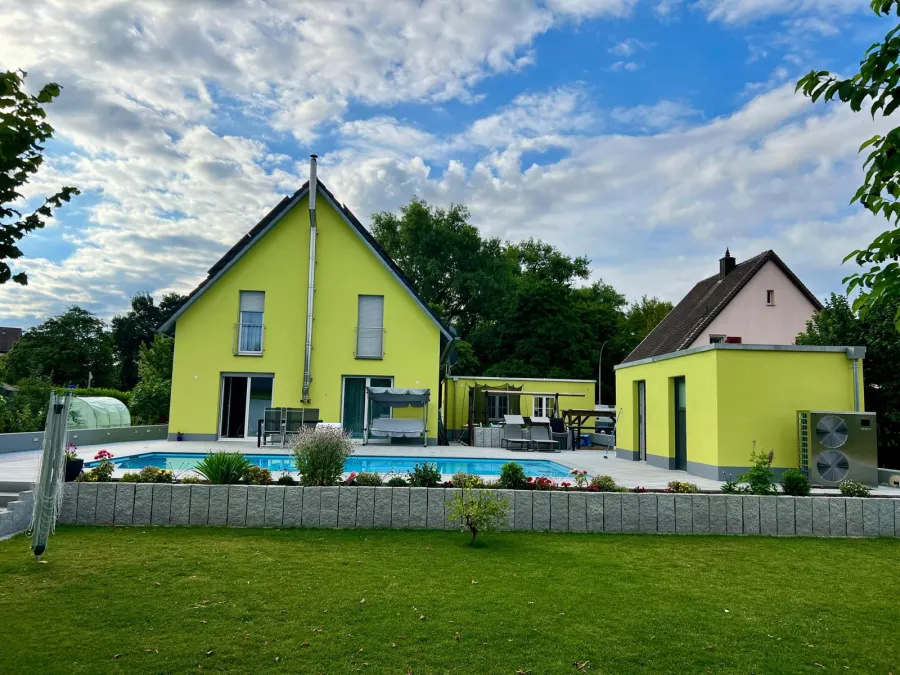 Gartenanlage mit Pool, Terrasse und Sitzbereich am hellgrünen Haus