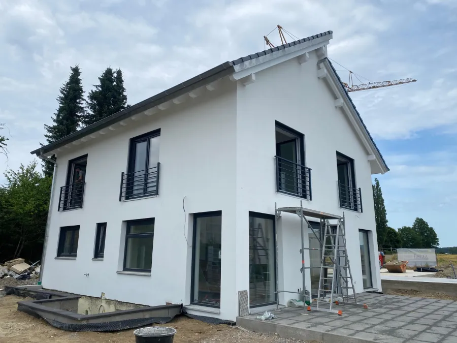 Hausfassade mit Fenstergeländern, Baumaterial und Kran im Hintergrund