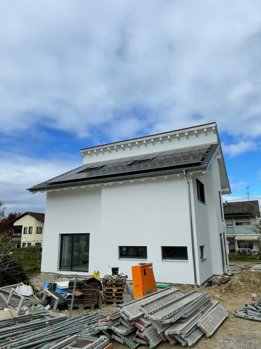 Hausdach mit Photovoltaikanlage, Baumaterial liegt noch im Garten