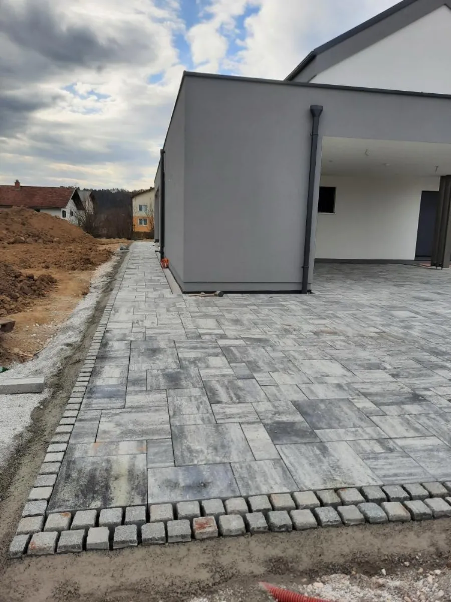 Großformatige Pflasterplatten mit Natursteinrand an moderner Hauseinfahrt