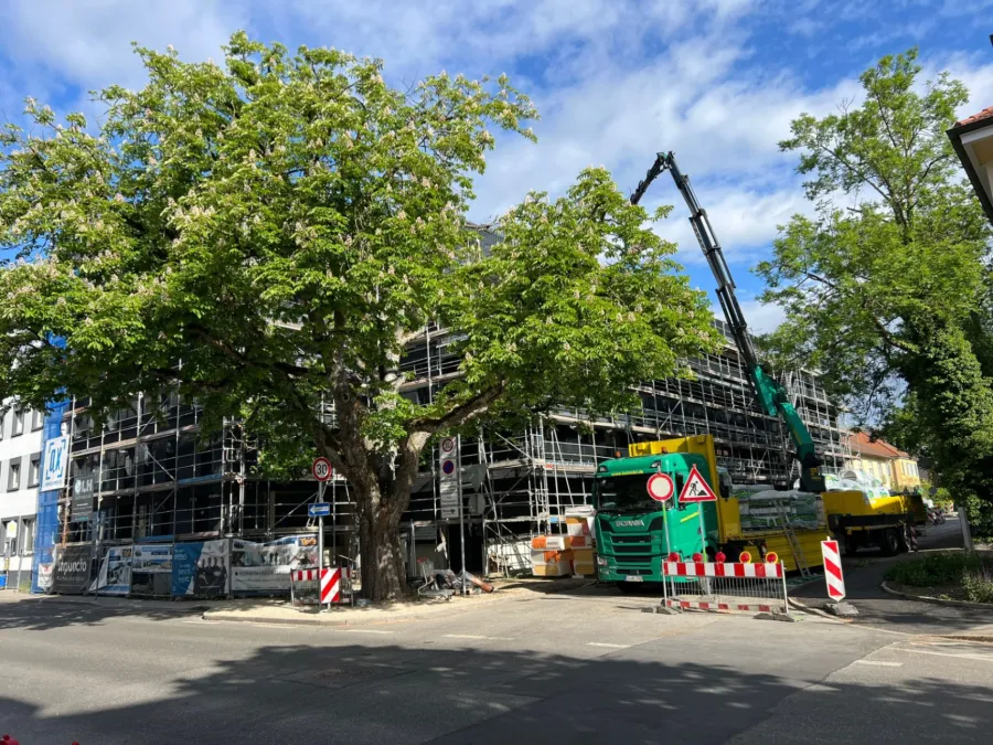 Eingerüstete Hausfassade auf einer Baustelle mit Kranfahrzeug im Straßenraum